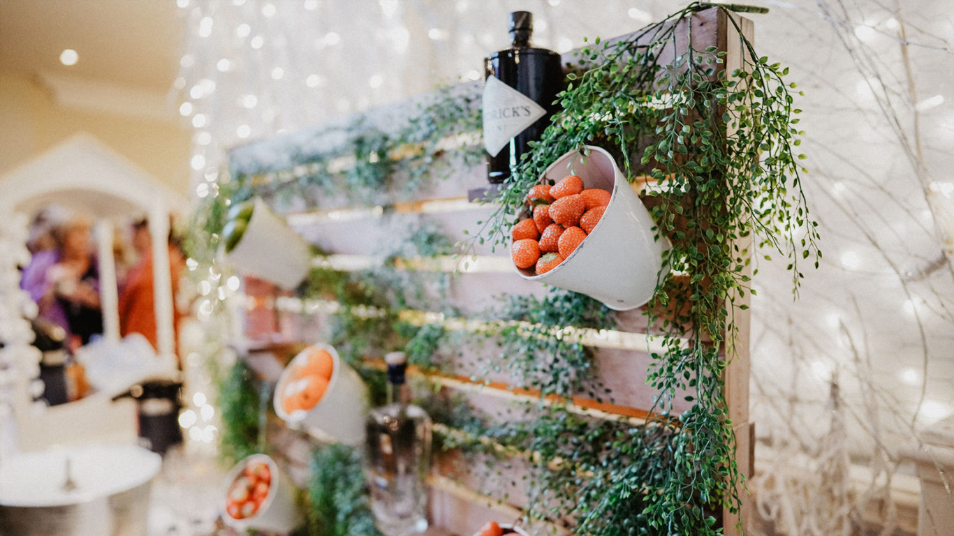 Charming hotel cocktail bar with greenery, strawberries in pots, creating a cosy, festive atmosphere.