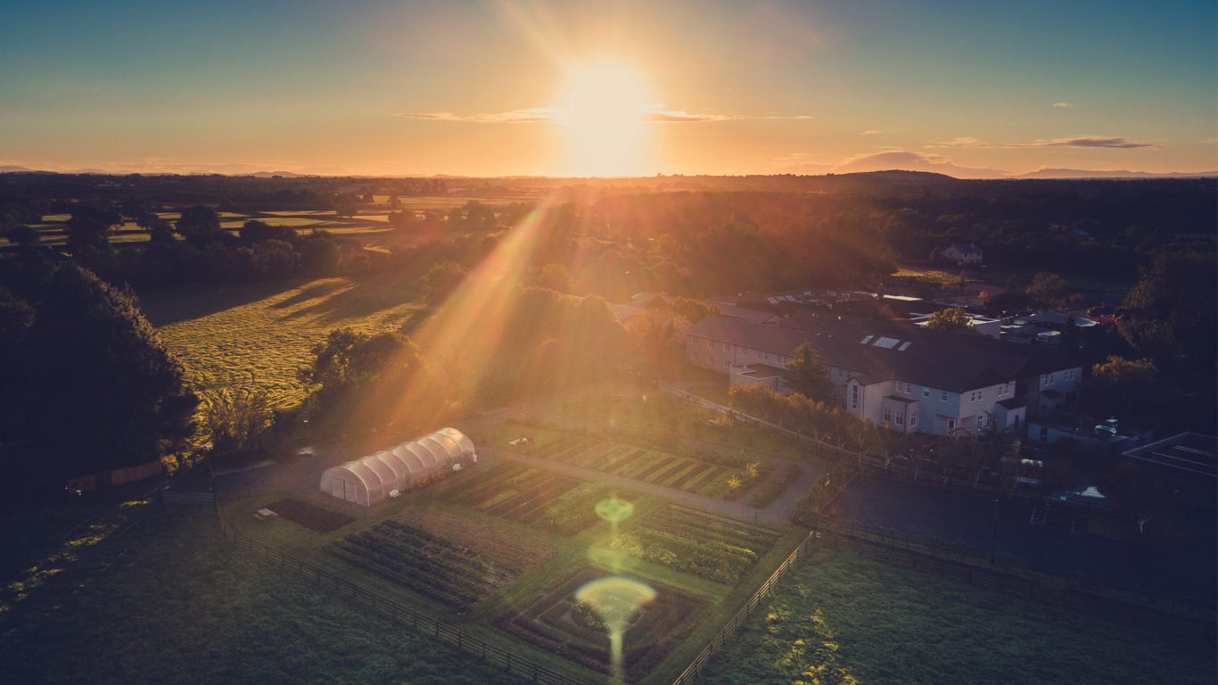 Drone shot of Fitzgeralds Woodlands Hotel grounds looking over to Adare Manor at sunset