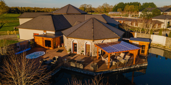 Serene hotel terrace with sun loungers, jacuzzi, and scenic countryside views, offering a relaxing retreat by the water.
