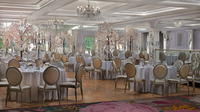 Elegant ballroom with round tables, floral centrepieces, chandeliers, and plush chairs, perfect for weddings and events.