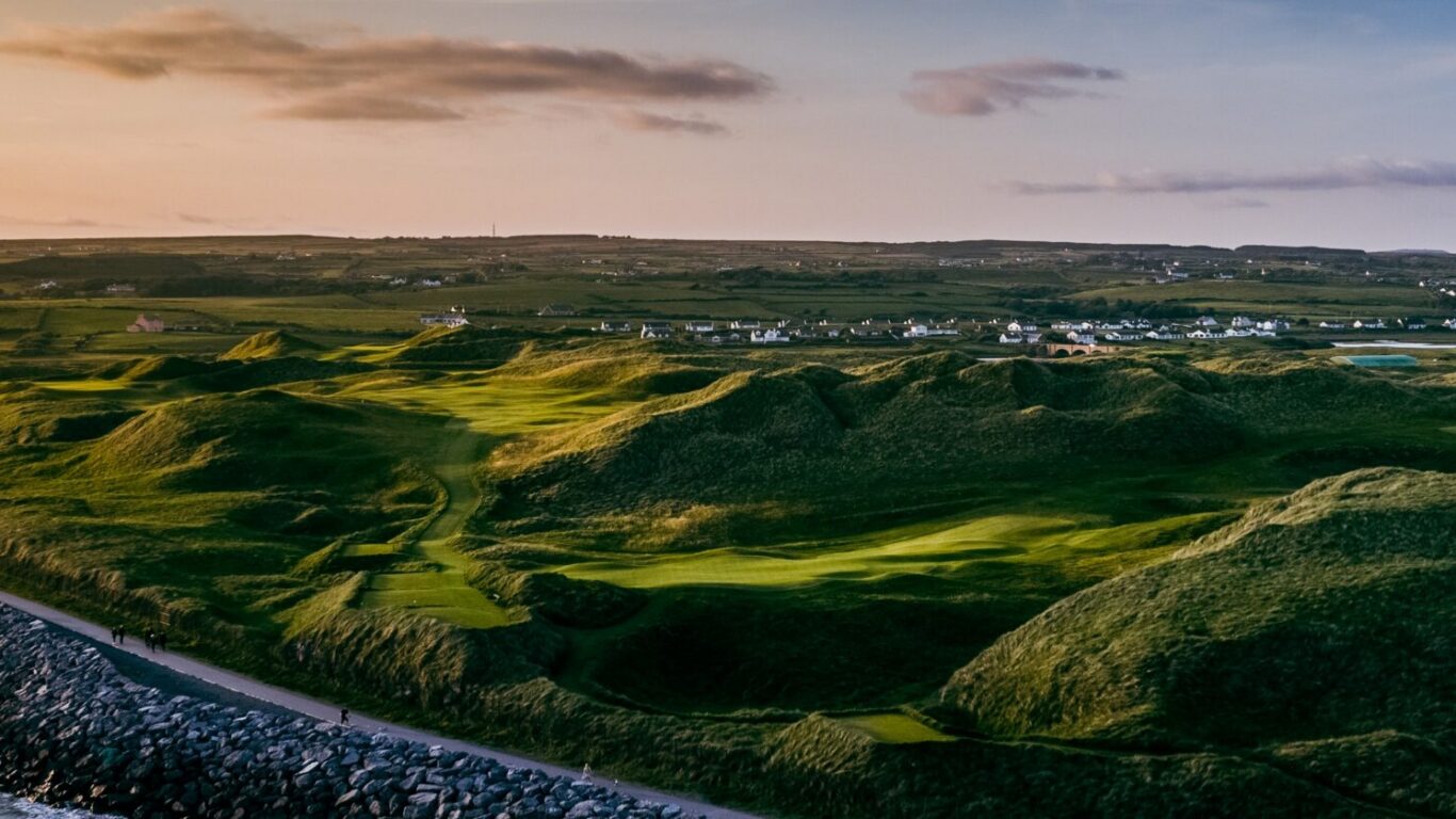 Stunning seaside landscape with rolling green hills, pristine beaches, and charming coastal village at sunset near our hotel.