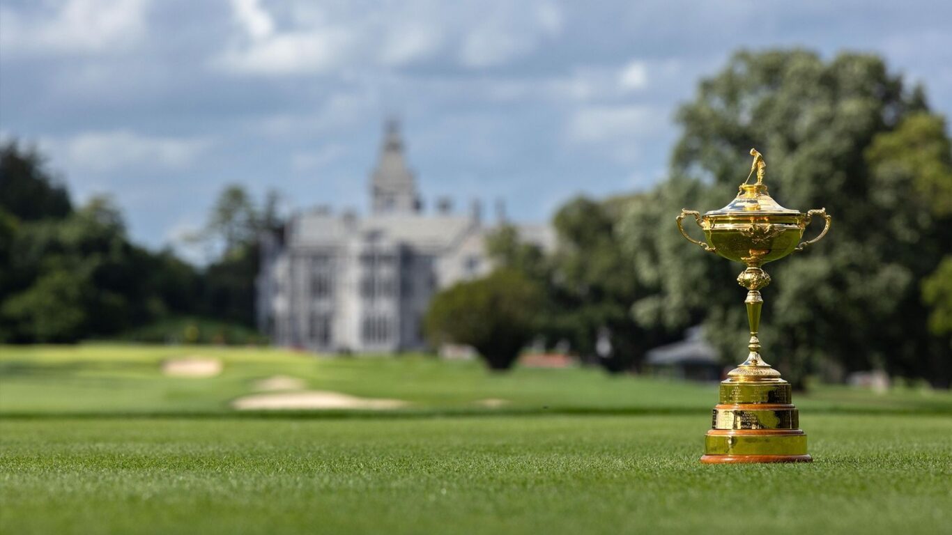 Stunning hotel frontage with lush golf course and elegant trophy in foreground, perfect for luxury golfing retreats.