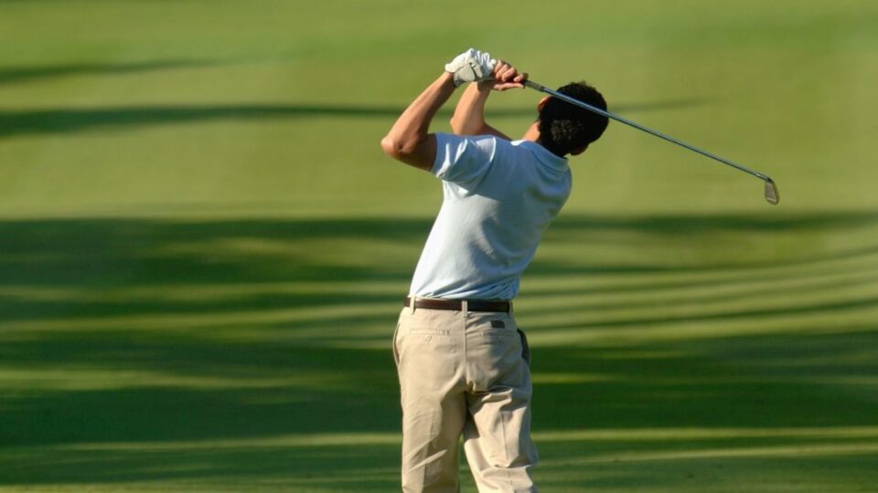 Guest enjoys a sunny day golfing on our lush, scenic course surrounded by greenery, perfect for a relaxing hotel stay.