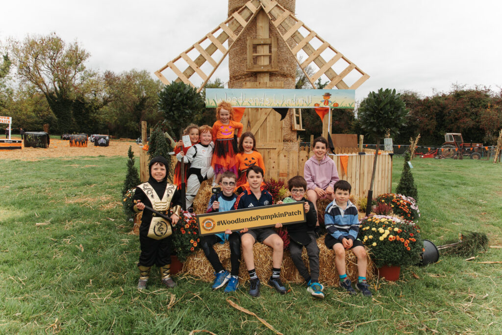 Children enjoy festive autumn activities at Woodland's pumpkin patch, surrounded by hay bales and colourful decorations.