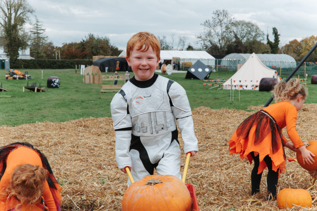 Children in costumes enjoy a festive autumn day with pumpkins and games in a charming countryside setting.
