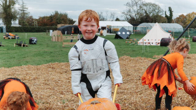 Children in costumes enjoy a festive autumn day with pumpkins and games in a charming countryside setting.