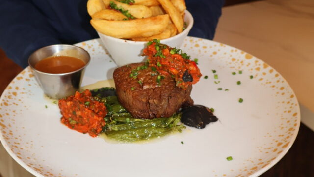Gourmet steak with rich sauce and thick-cut chips at our hotel's fine dining restaurant, offering a luxury culinary experience.