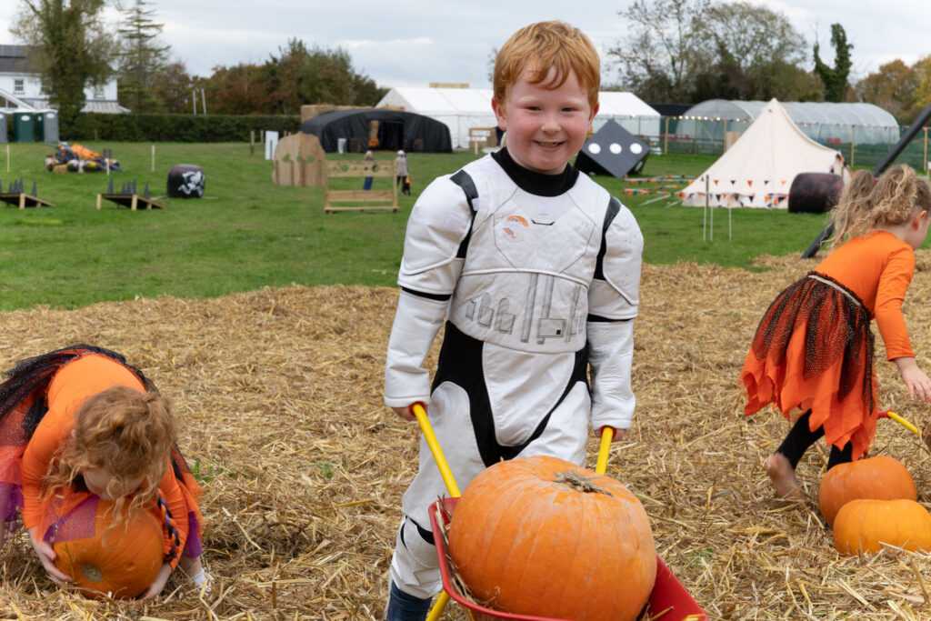 Children in costumes enjoy a fun pumpkin patch activity at a family-friendly hotel with scenic gardens and play areas.