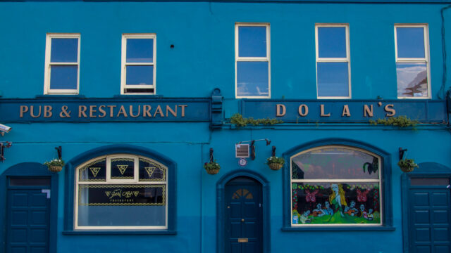 Vibrant blue facade of Dolan's Pub & Restaurant, welcoming guests with classic charm and colourful decor.
