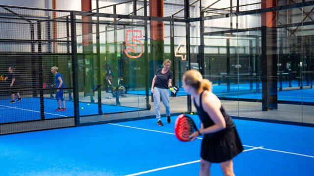Guests enjoying a lively padel match on vibrant blue courts at our luxury hotel's sports facility, perfect for active stays.