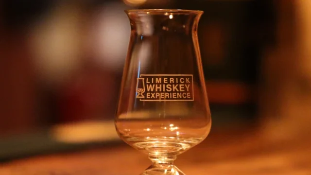 Experience Limerick Whiskey with this elegant glass on a rustic bar, promising a warm Irish welcome.