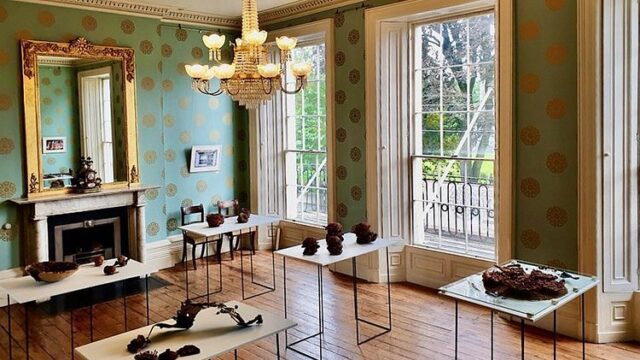 Elegant hotel lounge with vintage decor, chandeliers, and large windows offering garden views; ideal for relaxation.